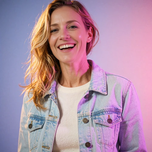 Portrait of a cheerful woman in a pale denim jacket laughing in soft pink light